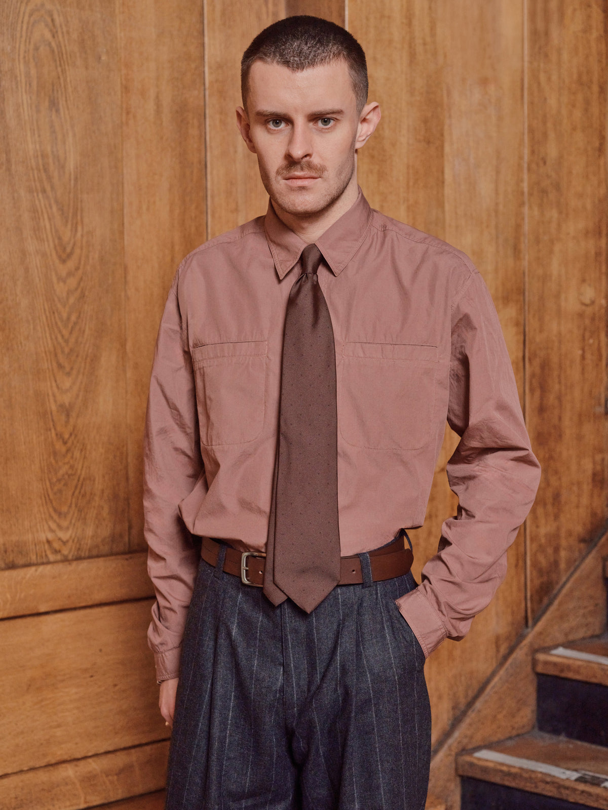 Man wearing a dusty pink cotton shirt with patch pockets and a brown wool tie