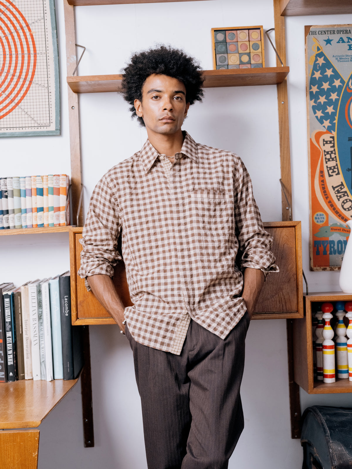 Brown check shirt with brown pleated trousers at the bookcase.