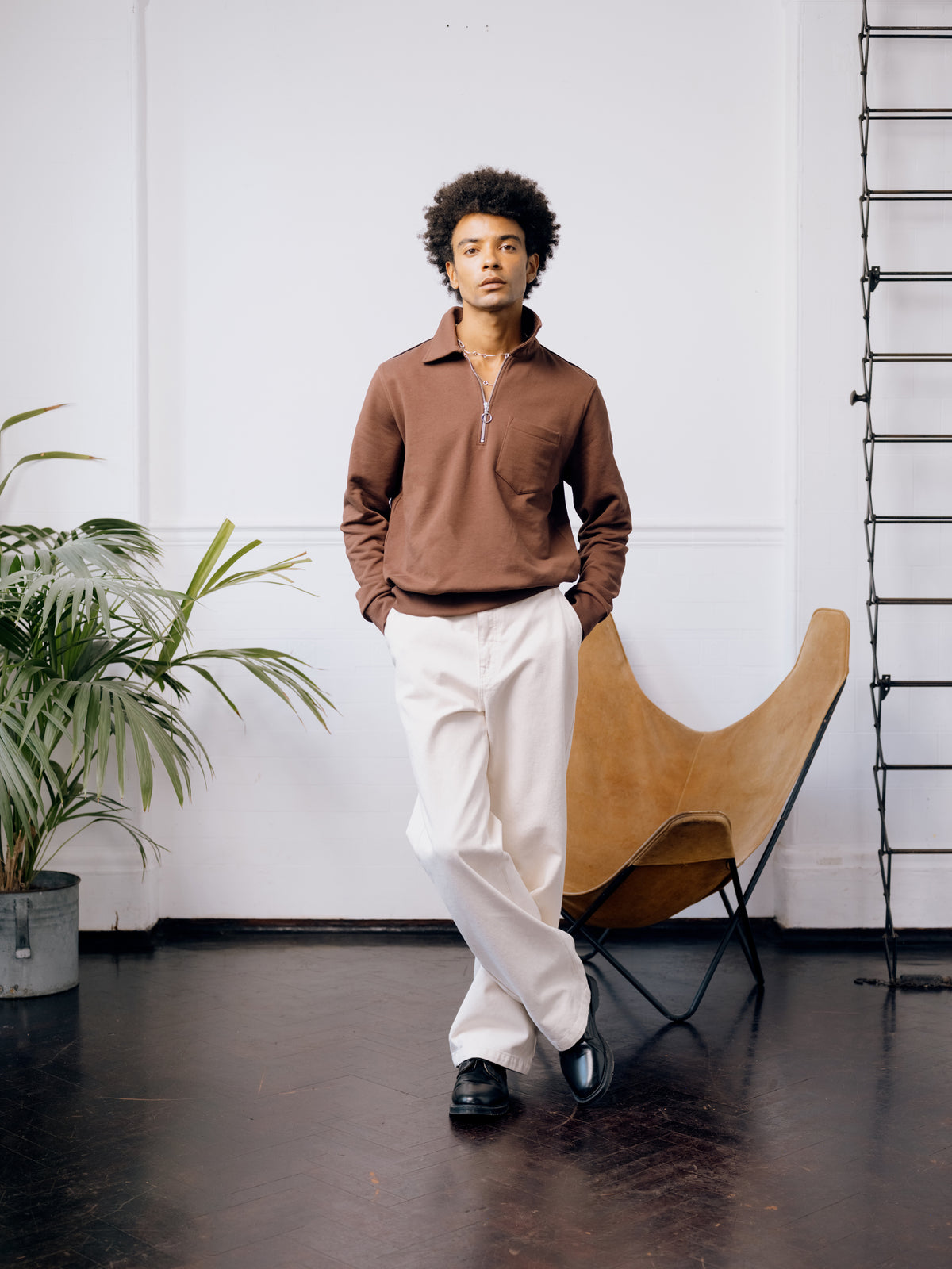 Rust half-zip sweatshirt with ecru straight leg trousers and black Gibson shoes.