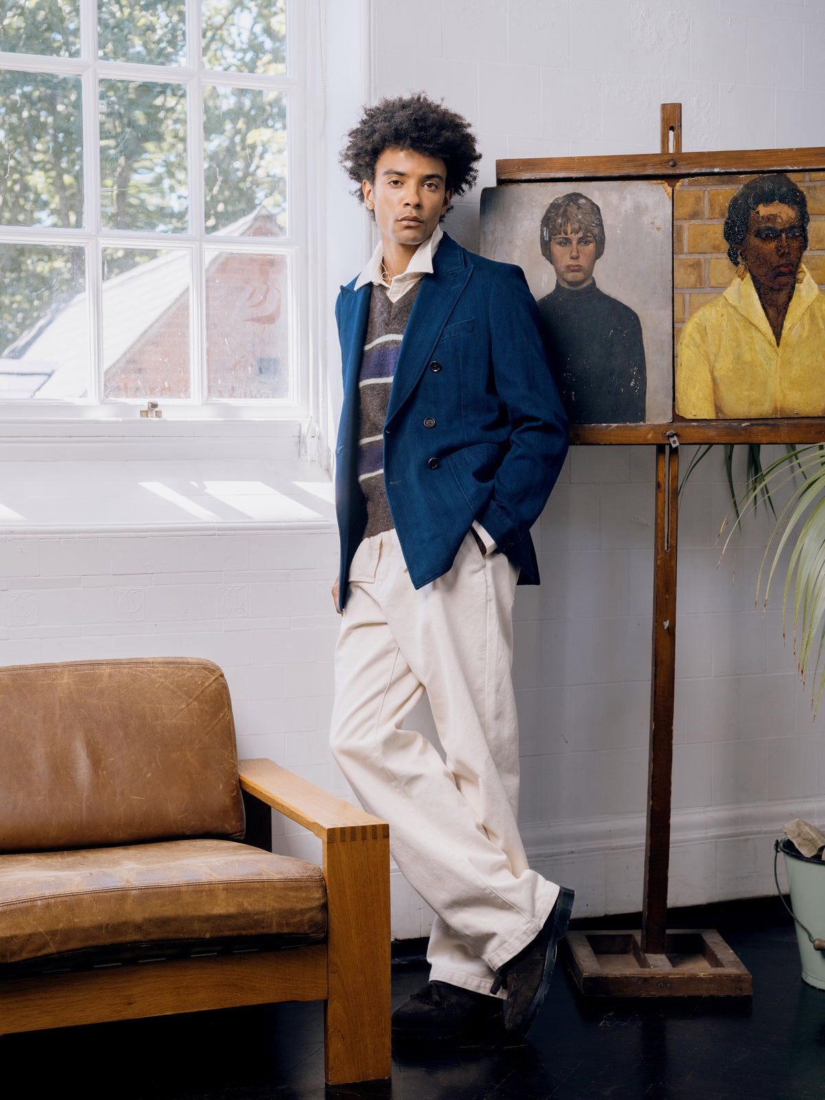Indigo double breasted jacket over a striped knitted vest with ecru trousers and brown suede shoes.