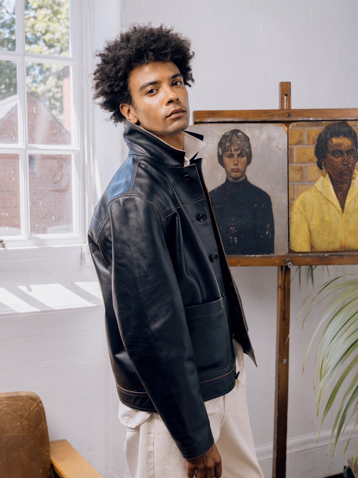 Black leather Hardwick jacket worn with the collar up over ecru trousers.