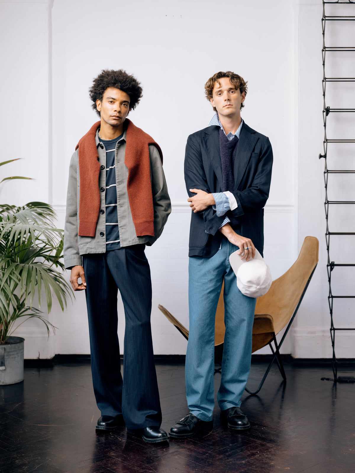 Two models beside the ladder. One in a green Kennard jacket and navy striped T-shirt with a red jumper over the shoulders, the other in a pinstripe Westbury jacket over a striped shirt and purple knitted vest.