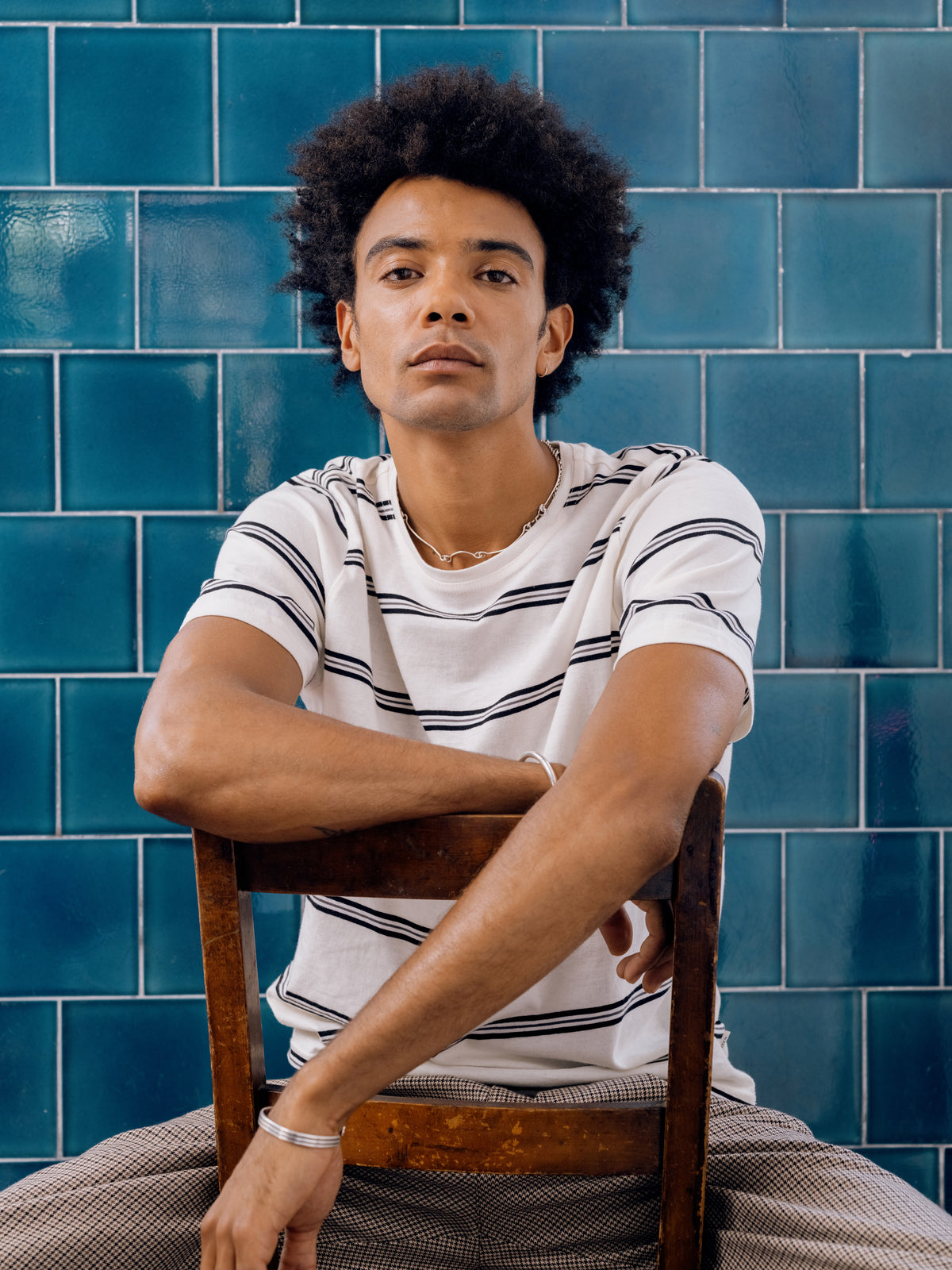 Cream and navy striped T-shirt, arm resting over the chair back.