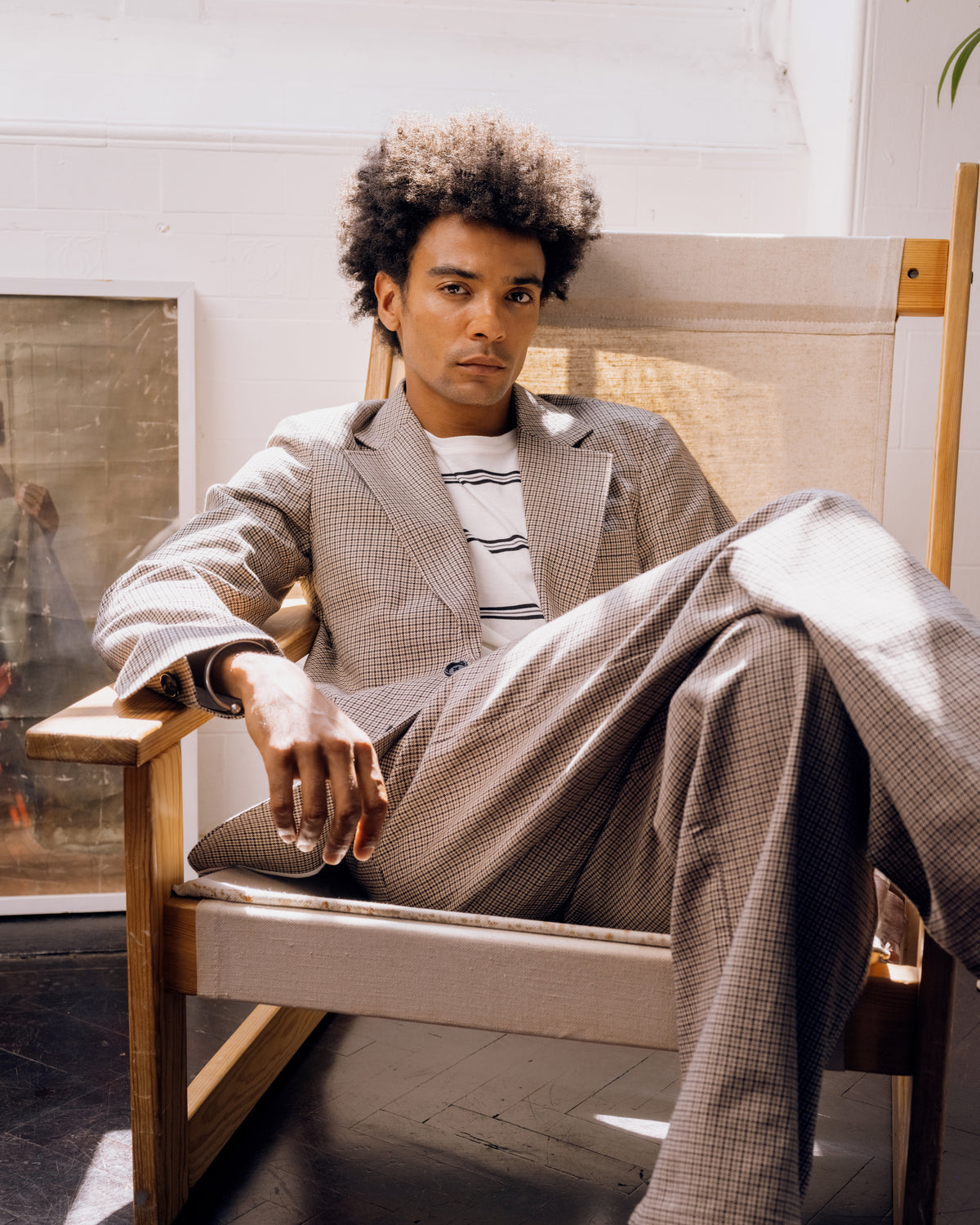 Houndstooth suit, seated, jacket open over a striped T-shirt.