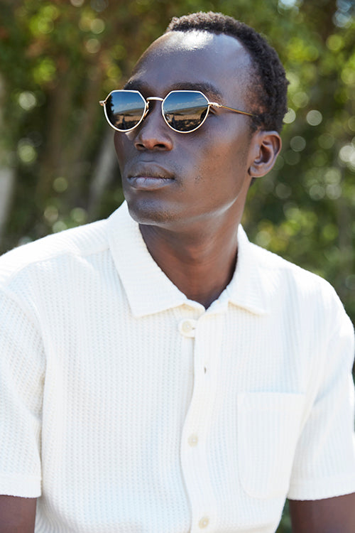 Oliver Spencer Spring 21, look 10. Portrait in a white short sleeve pocket shirt and sunglasses.