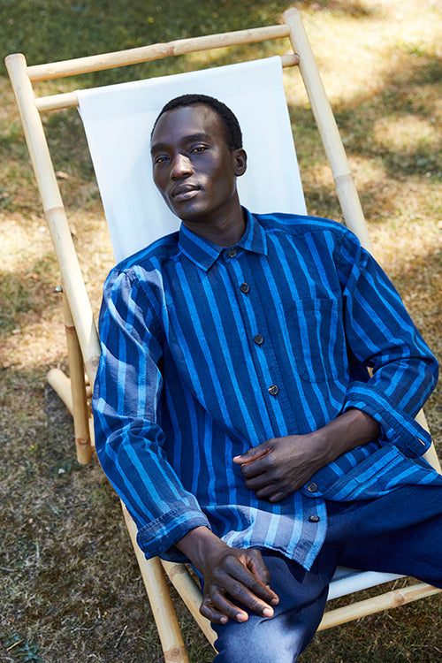 Oliver Spencer Spring 21, look 11. Blue striped shirt, seated in a painted white frame.