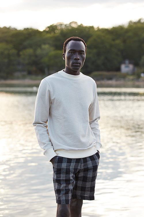 Oliver Spencer Spring 21, look 27. Oatmeal sweatshirt photographed by a lake.